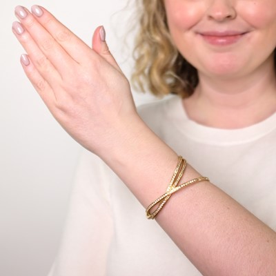 Lot 45 - Cartier Gold and Diamond 'Trintiy' Rolling Bangle Bracelet, France
