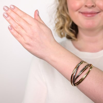 Lot 51 - Cartier Tricolor Gold Seven Band 'Trinity' Rolling Bangle Bracelet, France
