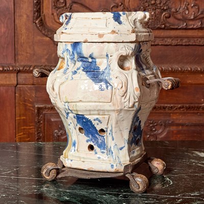 Lot 521 - IRON AND WOOD-MOUNTED CONTINENTAL FAIENCE PORTABLE STOVE AND COVER ON WHEELED METAL BASE
