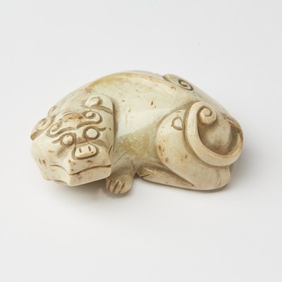 Lot 16 - A Chinese Calcified Jade Carving of a Recumbent Foo Dog